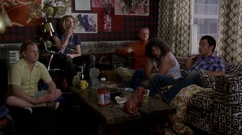 Movie still from “Lady in the Water” (2006), directed by M. Night Shyamalan – A group of people sitting on a couch in a living room; Wide shot, High angle