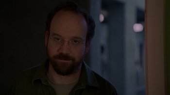 Movie still from “Lady in the Water” (2006), directed by M. Night Shyamalan – A man with a goatee wearing glasses and a green shirt; Close Up shot, Over the shoulder angle