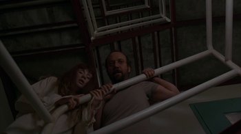 Movie still from “Lady in the Water” (2006), directed by M. Night Shyamalan – A man and a woman hanging from a metal bar; Medium shot, Low angle