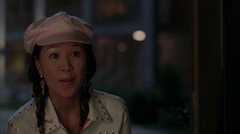 Movie still from “Lady in the Water” (2006), directed by M. Night Shyamalan – A woman wearing a pink hat standing in front of a building at night; Close Up shot, High angle