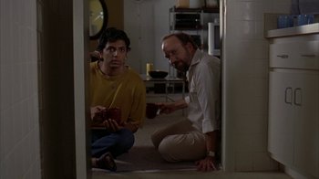 Movie still from “Lady in the Water” (2006), directed by M. Night Shyamalan – Two men sitting on the ground in a room; Medium shot, Over the shoulder angle
