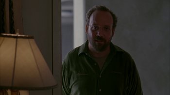 Movie still from “Lady in the Water” (2006), directed by M. Night Shyamalan – A man in a green shirt is standing by a lamp; Medium shot, Over the shoulder angle
