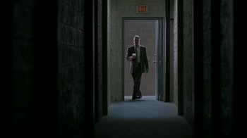 Movie still from “Lady in the Water” (2006), directed by M. Night Shyamalan – A man in a suit and tie walking down a hall way; Wide shot, Low angle