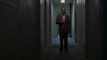 Movie still from “Lady in the Water” (2006), directed by M. Night Shyamalan – A man in a suit and tie standing in a hallway; Wide shot, Low angle