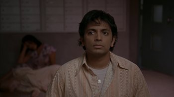Movie still from “Lady in the Water” (2006), directed by M. Night Shyamalan – A man in a brown and white striped shirt looking to his left; Close Up shot, Over the shoulder angle