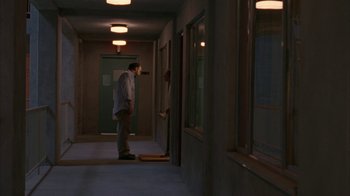 Movie still from “Lady in the Water” (2006), directed by M. Night Shyamalan – A man standing in a hallway looking in a mirror; Wide shot, High angle