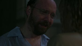 Movie still from “Lady in the Water” (2006), directed by M. Night Shyamalan – A man with a goatee wearing glasses and a blue shirt; Close Up shot, Over the shoulder angle