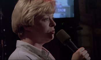 Movie still from “Ladybird Ladybird” (1994), directed by Ken Loach – A person holding a microphone in their hand; Close Up shot, Low angle