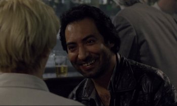 Movie still from “Ladybird Ladybird” (1994), directed by Ken Loach – A man smiling at the camera while sitting at a table; Close Up shot, Over the shoulder angle