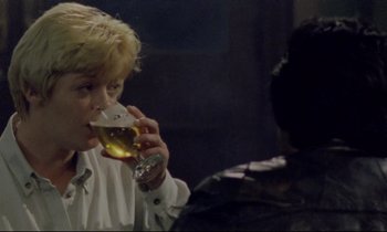 Movie still from “Ladybird Ladybird” (1994), directed by Ken Loach – A man drinking a beer while another man watches; Close Up shot, Over the shoulder angle