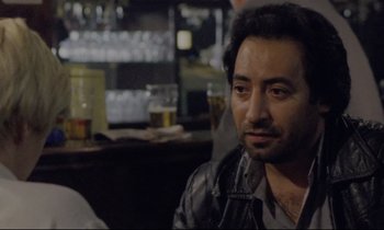 Movie still from “Ladybird Ladybird” (1994), directed by Ken Loach – A person sitting at a table in a room; Close Up shot, Over the shoulder angle