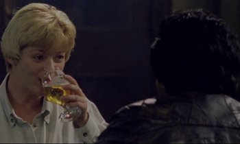Movie still from “Ladybird Ladybird” (1994), directed by Ken Loach – A woman drinking a glass of beer at a party; Close Up shot, Over the shoulder angle