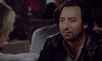 Movie still from “Ladybird Ladybird” (1994), directed by Ken Loach – A person sitting in a chair wearing a leather jacket; Close Up shot, Over the shoulder angle