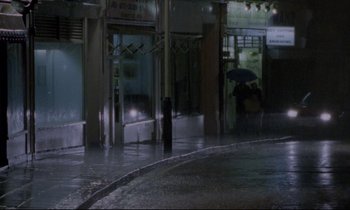 Movie still from “Ladybird Ladybird” (1994), directed by Ken Loach – Two people walking down the street with an open umbrella; Extreme Wide shot, High angle