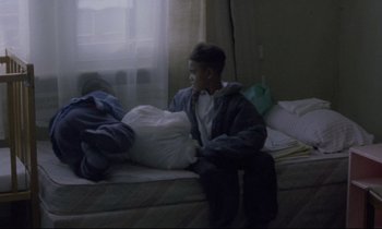 Movie still from “Ladybird Ladybird” (1994), directed by Ken Loach – Two young boys sitting on top of a bed next to pillows; Medium shot, High angle