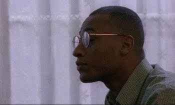Movie still from “Ladybird Ladybird” (1994), directed by Ken Loach – A person wearing glasses and a plaid shirt; Close Up shot, Low angle