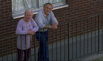 Movie still from “Ladybird Ladybird” (1994), directed by Ken Loach – An older man standing next to an older woman; Wide shot, High angle