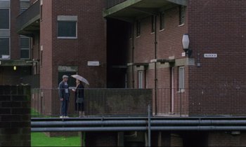 Movie still from “Ladybird Ladybird” (1994), directed by Ken Loach – A man and a woman standing under an umbrella; Extreme Wide shot, High angle