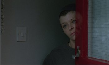 Movie still from “Ladybird Ladybird” (1994), directed by Ken Loach – A young man standing in front of a red door; Close Up shot, Overhead angle