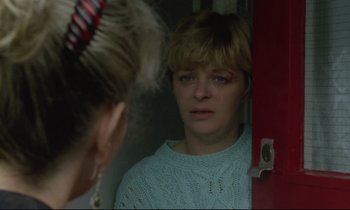 Movie still from “Ladybird Ladybird” (1994), directed by Ken Loach – A woman looking in the mirror in front of a red door; Close Up shot, Over the shoulder angle