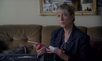Movie still from “Ladybird Ladybird” (1994), directed by Ken Loach – A woman sitting on a couch holding a magazine; Close Up shot, Over the shoulder angle