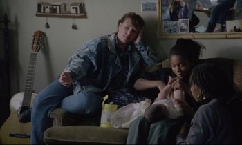 Movie still from “Ladybird Ladybird” (1994), directed by Ken Loach – A group of people sitting on top of a brown couch; Medium shot, High angle