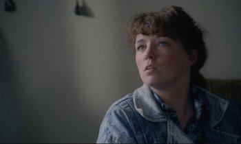 Movie still from “Ladybird Ladybird” (1994), directed by Ken Loach – A woman in a denim jacket looking up at the ceiling; Close Up shot, Over the shoulder angle