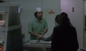 Movie still from “Ladybird Ladybird” (1994), directed by Ken Loach – A man wearing a paper chef's hat in front of a woman in a kitchen; Medium shot, Over the shoulder angle