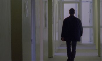 Movie still from “Ladybird Ladybird” (1994), directed by Ken Loach – A man walking down a hall way in a building; Wide shot, Low angle
