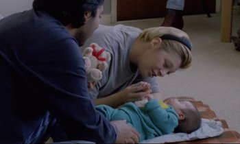 Movie still from “Ladybird Ladybird” (1994), directed by Ken Loach – A man and a woman are playing with a baby; Medium shot, High angle