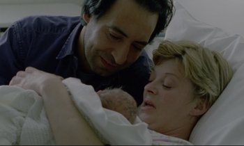 Movie still from “Ladybird Ladybird” (1994), directed by Ken Loach – A man and a woman holding a baby in a hospital bed; Close Up shot, High angle