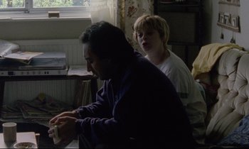 Movie still from “Ladybird Ladybird” (1994), directed by Ken Loach – A man and a boy playing a video game together; Medium shot, High angle