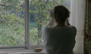 Movie still from “Ladybird Ladybird” (1994), directed by Ken Loach – A woman standing in front of a window looking outside; Medium shot, Over the shoulder angle