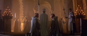 Movie still from “Ladyhawke” (1985), directed by Richard Donner – Two men dressed in medieval garb standing in front of a statue; Wide shot, High angle