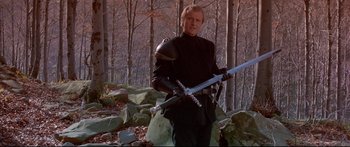 Movie still from “Ladyhawke” (1985), directed by Richard Donner – A man holding a sword in a forest; Medium shot, Low angle