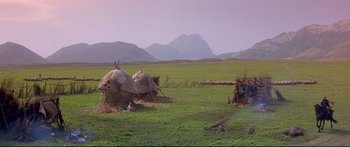 Movie still from “Ladyhawke” (1985), directed by Richard Donner – A group of people standing in the grass near some tents; Extreme Wide shot, High angle
