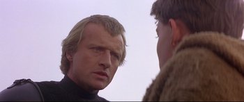 Movie still from “Ladyhawke” (1985), directed by Richard Donner – A man in a black shirt is looking at another man; Close Up shot, Over the shoulder angle