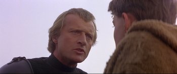 Movie still from “Ladyhawke” (1985), directed by Richard Donner – A man in a black shirt is talking to another man in a brown jacket; Close Up shot, Over the shoulder angle