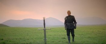 Movie still from “Ladyhawke” (1985), directed by Richard Donner – A man standing next to a sword in the middle of a field; Wide shot, Low angle