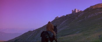 Movie still from “Ladyhawke” (1985), directed by Richard Donner – A man riding a horse down a hill at dusk; Wide shot, Low angle
