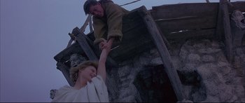 Movie still from “Ladyhawke” (1985), directed by Richard Donner – A man and a woman holding hands on top of a wooden structure; Wide shot, Low angle