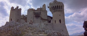 Movie still from “Ladyhawke” (1985), directed by Richard Donner – An old stone building with a tower in the middle of it; Extreme Wide shot, Low angle