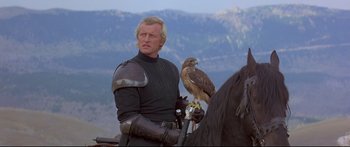 Movie still from “Ladyhawke” (1985), directed by Richard Donner – A man with a hawk on his arm and a falcon on his shoulder; Medium shot, Low angle
