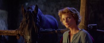 Movie still from “Ladyhawke” (1985), directed by Richard Donner – A woman standing next to a horse in a dark room; Close Up shot, Low angle