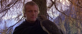 Movie still from “Ladyhawke” (1985), directed by Richard Donner – A man holding a bird in his arms; Close Up shot, Low angle