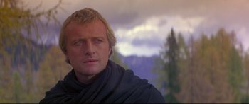 Movie still from “Ladyhawke” (1985), directed by Richard Donner – A person wearing a scarf with mountains in the background; Close Up shot, Low angle
