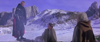 Movie still from “Ladyhawke” (1985), directed by Richard Donner – A man sitting in the snow under a blanket on top of a mountain; Wide shot, Low angle