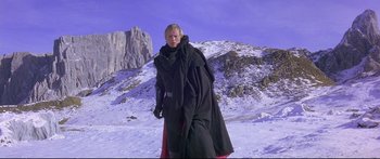 Movie still from “Ladyhawke” (1985), directed by Richard Donner – A woman in a long black coat standing in the snow; Wide shot, Low angle