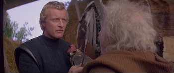 Movie still from “Ladyhawke” (1985), directed by Richard Donner – A man is talking to another man holding a flower; Close Up shot, Over the shoulder angle