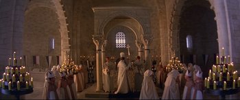 Movie still from “Ladyhawke” (1985), directed by Richard Donner – A group of people standing in a room with candles; Extreme Wide shot, High angle